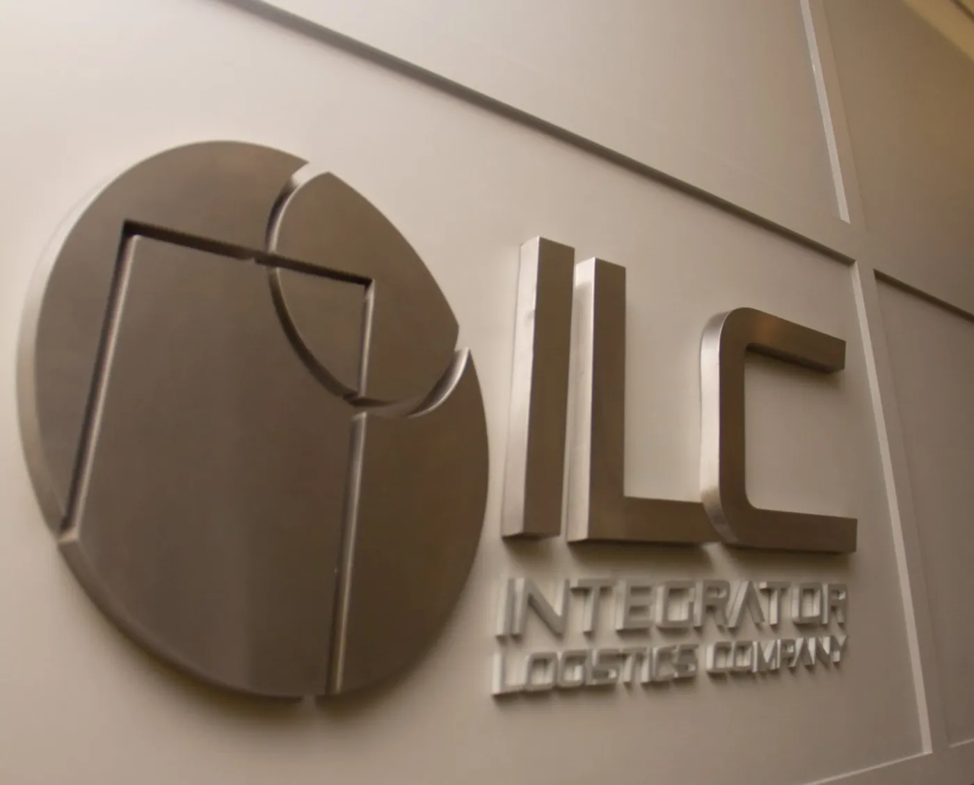 Logo da ILC em metal escovado na parede da recepção do escritório